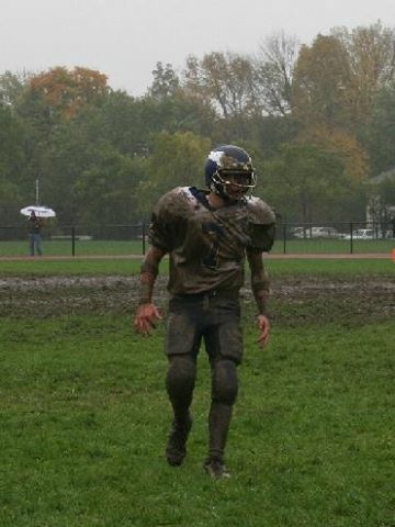 Muddy tackle football player walking off the field after a play